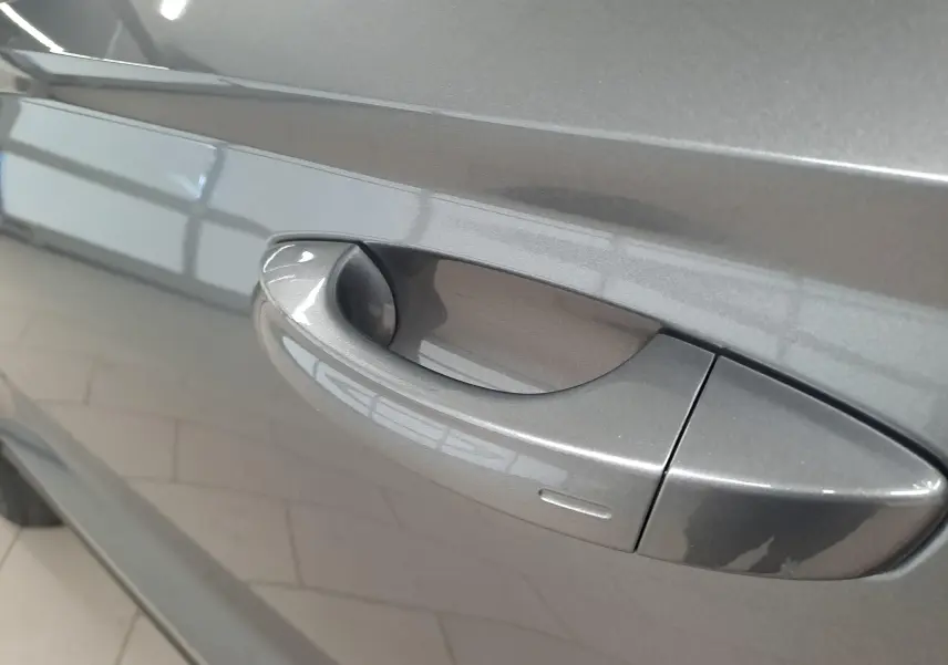 Poignée de porte côté droit du SEAT Ateca 2023 gris graphite métallisé en gros plan, reflet de lumière sur la carrosserie.