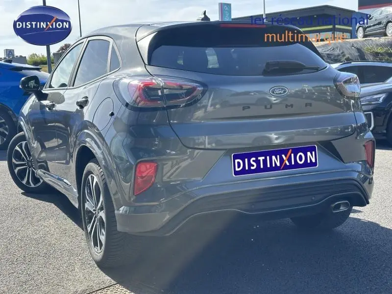 Vue 3/4 arrière droite d'un Ford Puma gris Solar métallisé 2023 avec feux arrière LED et logo distinctif sur le hayon.