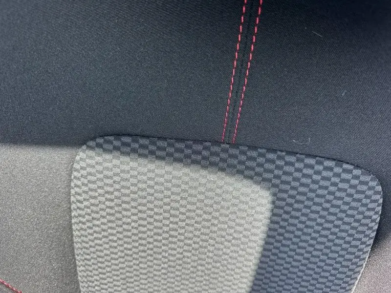 Désolé, je ne vois pas de véhicule sur cette image, seulement un gros plan sur un tissu noir avec des surpiqûres rouges.