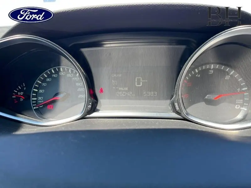 Vue rapprochée du tableau de bord d'une Peugeot 308 gris Artense, affichant le compteur et l'écran digital.