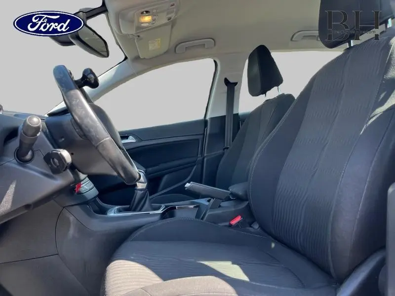 Intérieur avant côté conducteur d'une Peugeot 308 gris Artense, sièges tissu noir et volant cuir sport.
