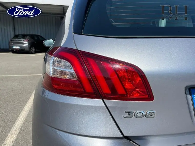 Gros plan sur le feu arrière droit gris Artense d'une Peugeot 308 avec logo et partie de la lunette arrière visible.
