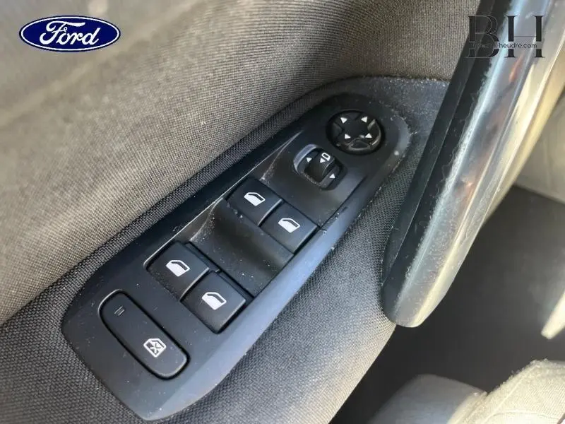 Gros plan sur les commandes des vitres électriques et rétroviseurs sur la porte intérieure d'une Peugeot 308 gris Artense.