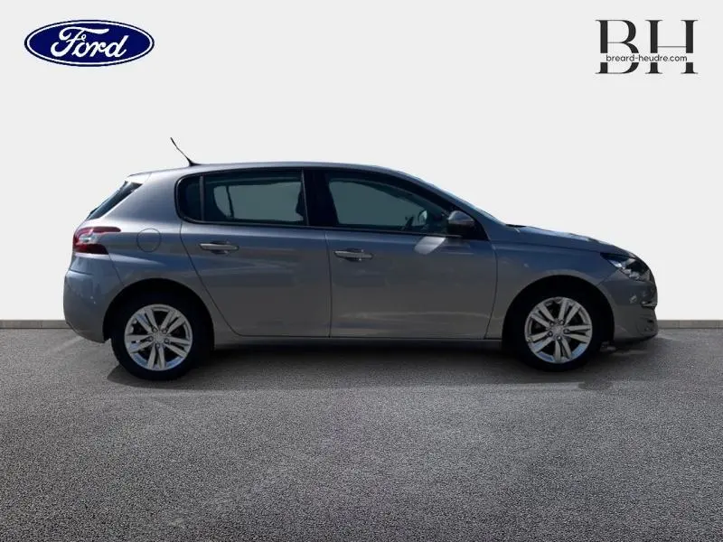 Profil droit d'une Peugeot 308 gris Artense de 2016 avec jantes alu et vitres teintées sur fond clair.