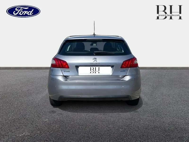 Vue arrière d'une Peugeot 308 gris Artense avec feux arrière rouges et logo au centre du hayon.