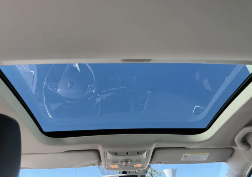 Vue intérieure du toit ouvrant panoramique du SEAT Leon blanc 2014, avec reflet du tableau de bord et ciel bleu visible.