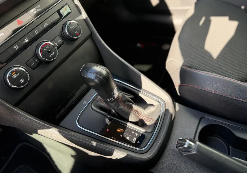 Gros plan sur la console centrale du SEAT LEON blanc, mettant en valeur le levier de vitesse automatique et les commandes de climatisation.