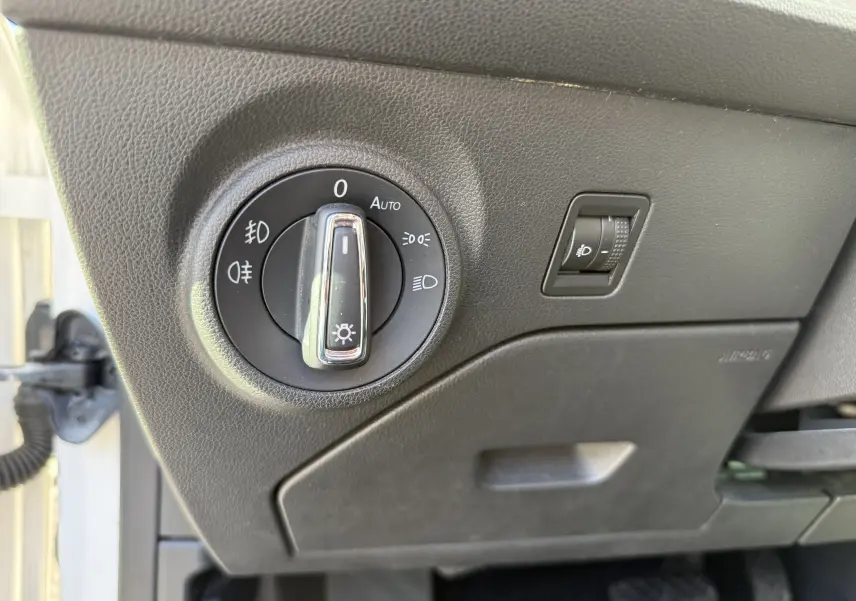 Gros plan sur le bouton de commande des phares et le réglage d’intensité lumineuse dans un SEAT Leon blanc 2014, côté conducteur.