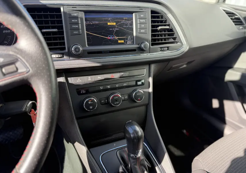 Vue intérieure centrée sur la console centrale d'une SEAT LEON 1.8 TFSI 2014, avec écran de navigation et levier de boîte auto.