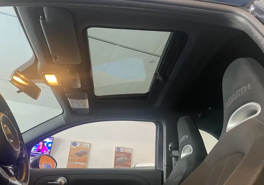 Vue intérieure du toit ouvrant électrique et des sièges baquets noirs Abarth d'une ABARTH 595 2018 côté conducteur.