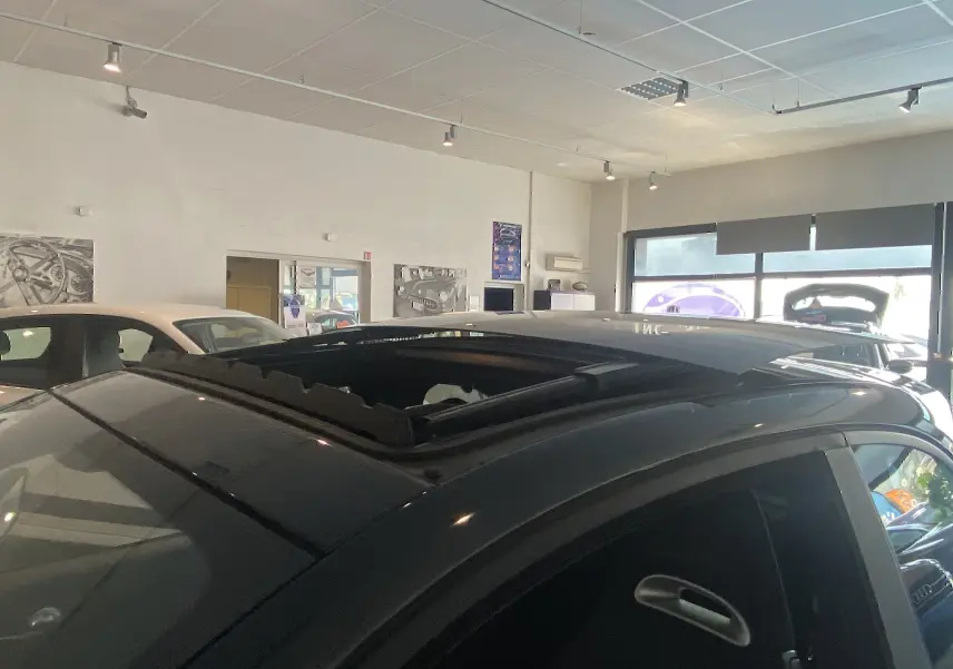 Toit ouvrant électrique ouvert vu de près sur le côté gauche d'une ABARTH 595 noire en showroom.