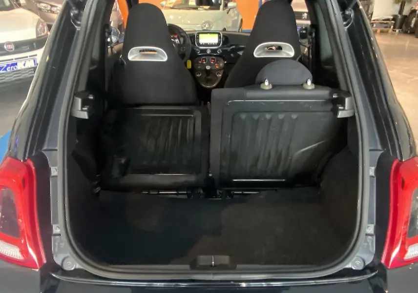 Vue arrière du coffre ouvert d'une ABARTH 595 noire, avec sièges arrière rabattus et tableau de bord visible.