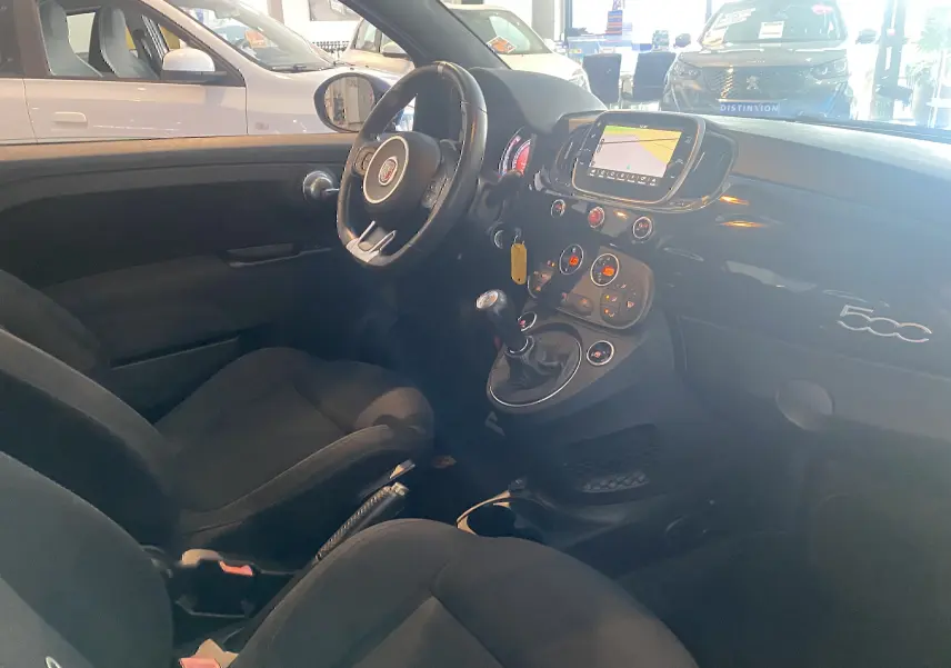Intérieur noir de l'Abarth 595 2018 vu côté conducteur, avec tableau de bord et écran GPS allumé.