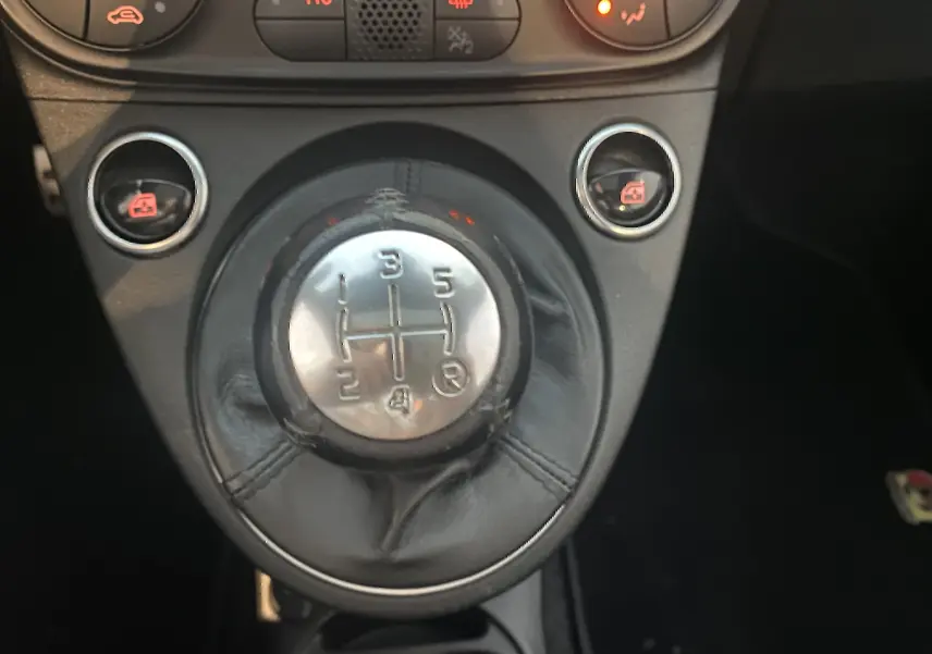 Gros plan sur le levier de vitesse manuelle en cuir noir de l'Abarth 595 2018 avec commandes de vitres électriques.