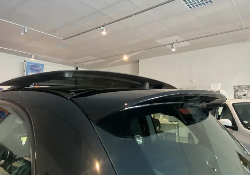 Vue rapprochée du toit ouvrant électrique et de l'aileron arrière d'une ABARTH 595 noire en intérieur showroom.