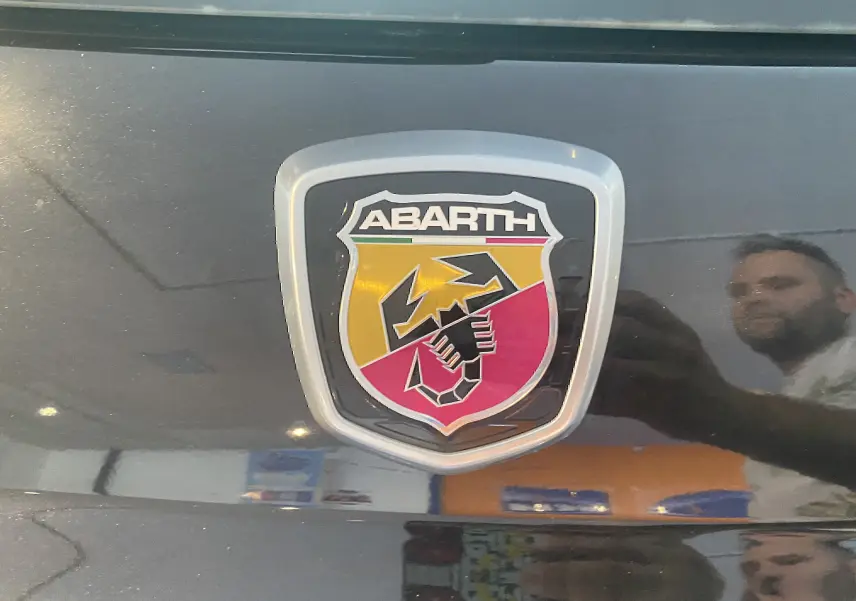 Gros plan sur le logo Abarth noir et rouge sur la calandre d'une ABARTH 595 noire de 2018.