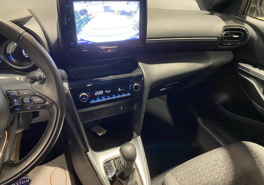 Intérieur noir de la Toyota Yaris Cross 116H, vue du tableau de bord côté conducteur avec écran tactile et caméra de recul affichée.