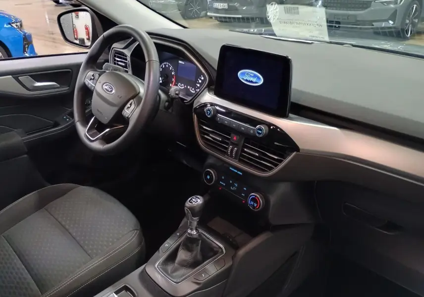 Vue intérieure côté conducteur du Ford Kuga 2024 avec tableau de bord moderne et écran tactile central allumé.