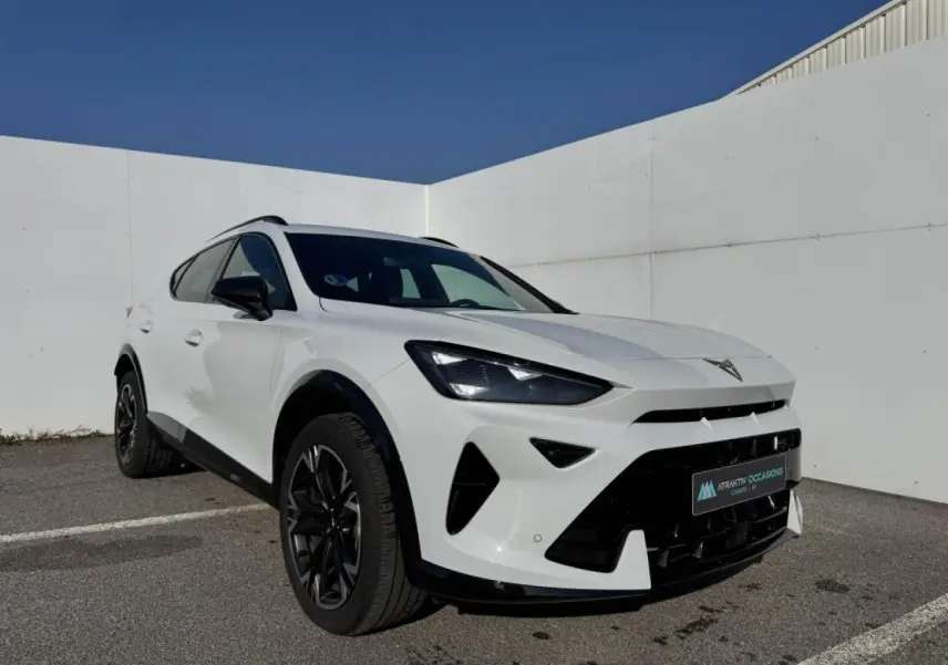 Vue 3/4 avant droit d'une CUPRA Formentor blanc nacré avec toit noir et jantes alliage noires dans un parking extérieur.