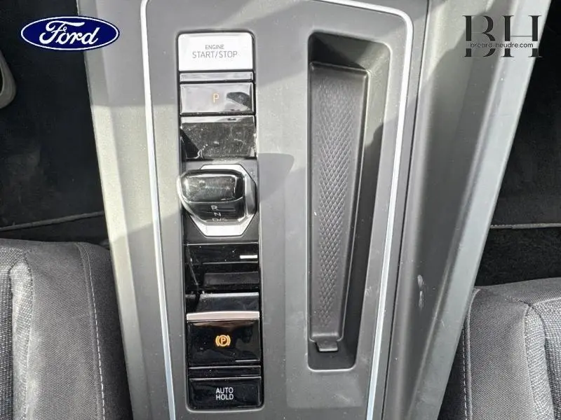 Vue rapprochée de la console centrale grise lunaire de la Volkswagen Golf 2023 avec levier de vitesse automatique et frein à main électronique.