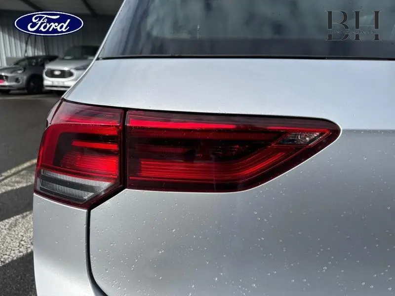 Gros plan sur le feu arrière droit d'une Volkswagen Golf gris lunaire 2023 sous la pluie.