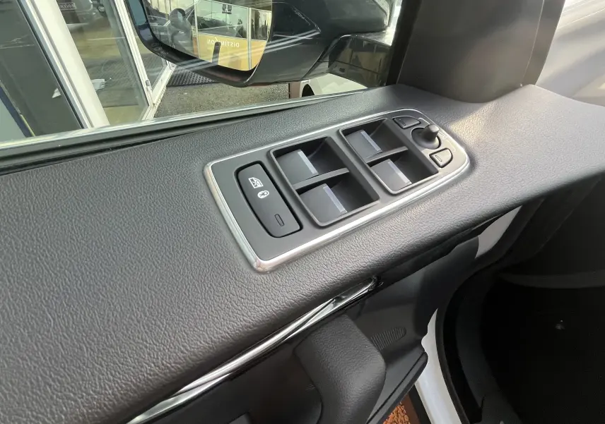 Détail des commandes des vitres sur la porte avant gauche d’un Jaguar F-PACE blanc, vue intérieure.