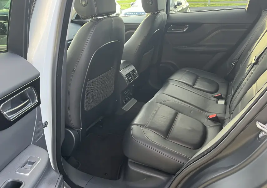Vue intérieure côté droit des sièges arrière en cuir noir du Jaguar F-PACE blanc 2018, avec porte ouverte.