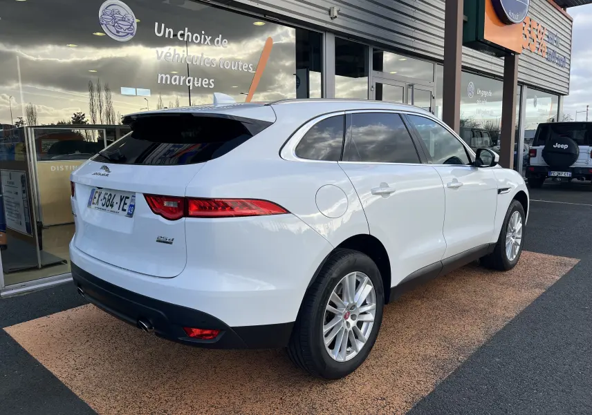 Jaguar F-PACE blanc vue 3/4 arrière droit, avec feux LED et jantes alliage 19 pouces visibles.