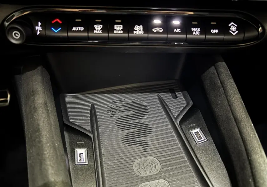 Gros plan sur la console centrale de l'Alfa Romeo Junior 2024, montrant la zone de recharge sans fil avec logo serpent.