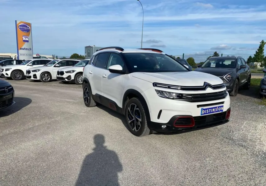 Citroën C5 Aircross blanc 3/4 avant droit avec inserts Deep Red anodisé et barres de toit bi-ton visibles.