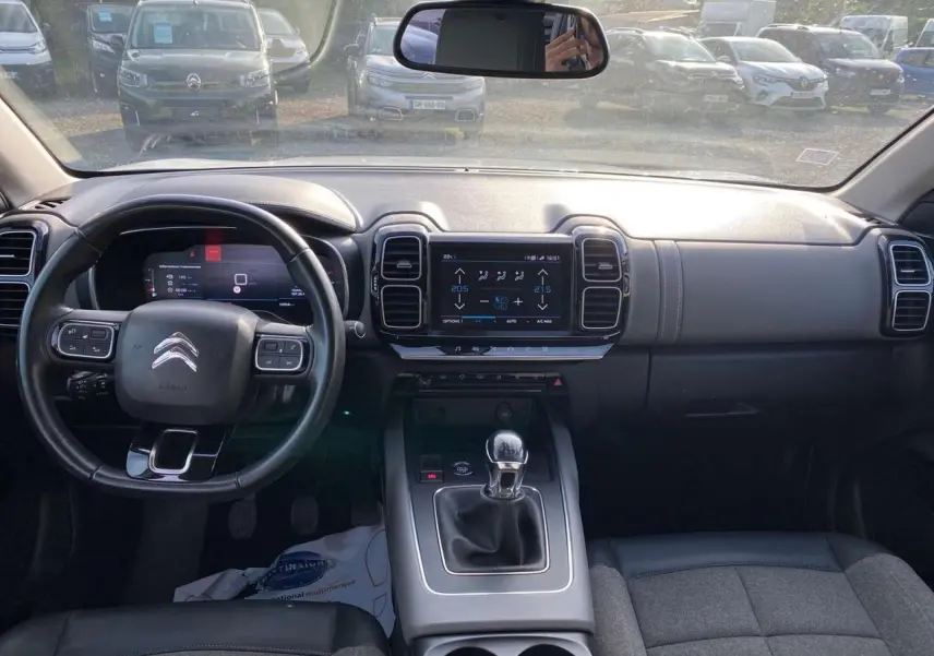 Vue intérieure avant du Citroën C5 Aircross blanc avec tableau de bord noir, volant cuir et boîte manuelle.