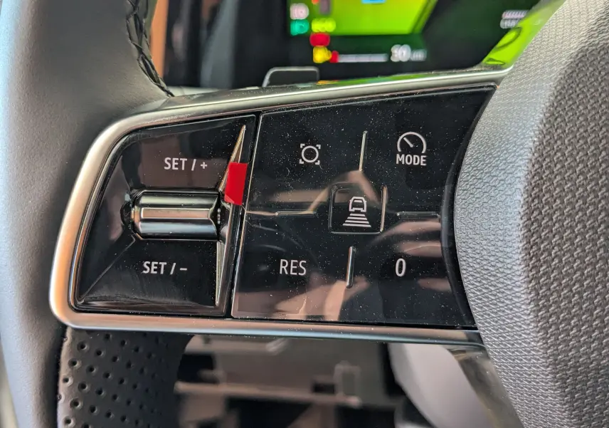 Gros plan sur les commandes de régulateur de vitesse au volant du Renault Austral blanc nacré, affichage numérique en arrière-plan.