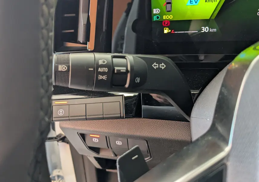 Gros plan sur la manette de clignotants et tableau de bord numérique du Renault Austral E-Tech blanc nacré, intérieur moderne.
