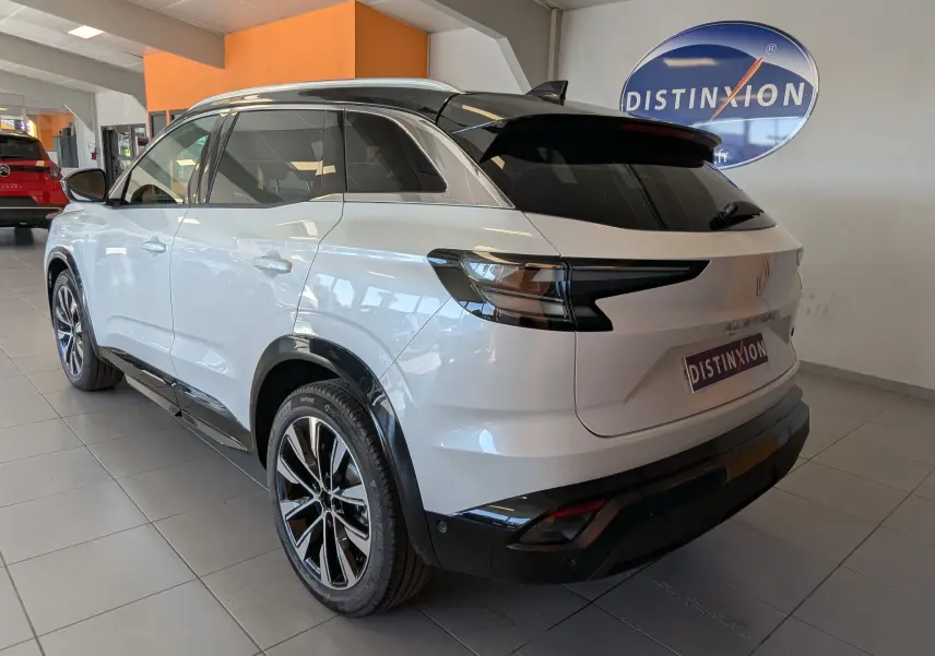 Vue 3/4 arrière droite du Renault Austral blanc nacré avec toit noir et jantes alliage 19 pouces en showroom.