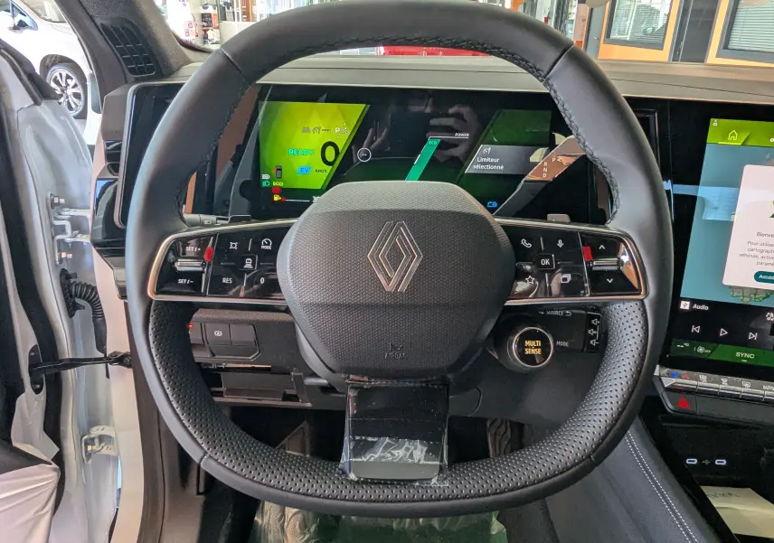 Vue intérieure centrée sur le volant Renault du Renault Austral E-Tech 200, avec tableau de bord numérique et écran tactile visible.
