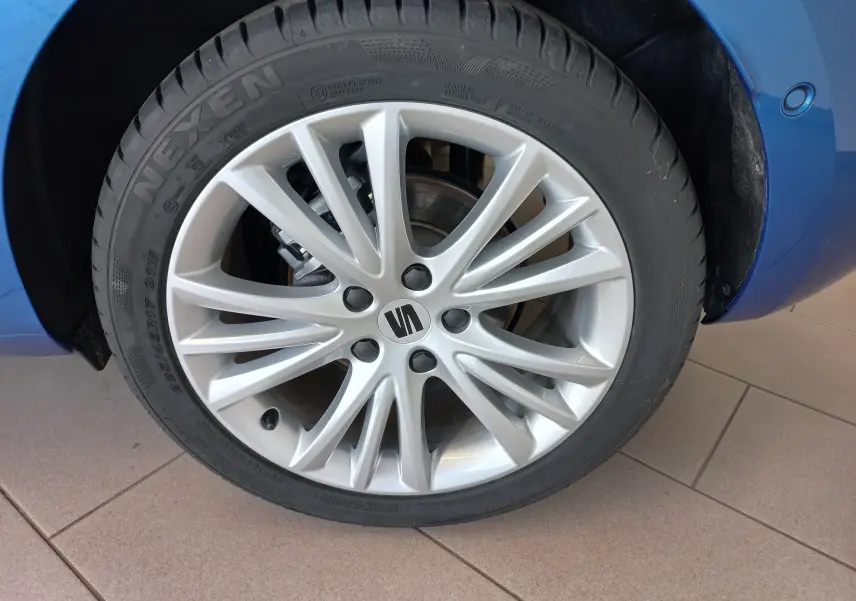 Gros plan sur la roue avant droite d'une SEAT LEON Bleu Saphir, mettant en valeur la jante alliage argentée au design fin.