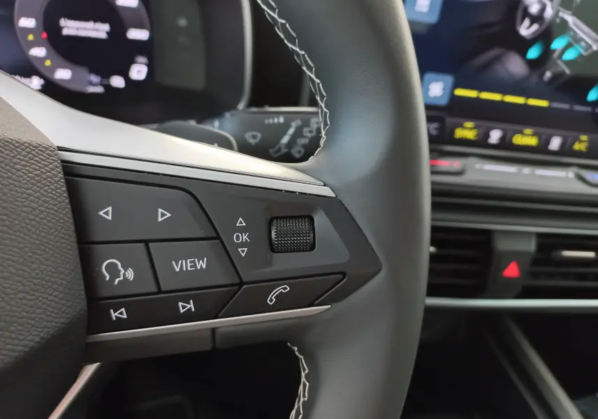 Gros plan sur les commandes au volant gauche d’un SEAT LEON 1.5 eTSI 115 DSG7 COPA, intérieur moderne avec écran tactile.