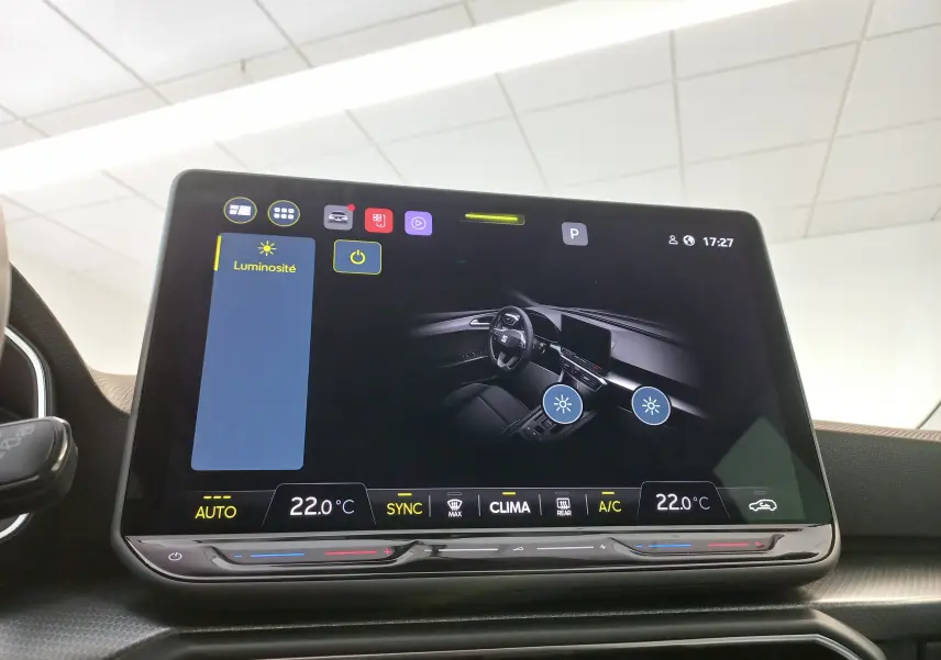 Écran tactile central affichant les réglages de luminosité et climatisation dans une SEAT LEON Bleu Saphir 2025.
