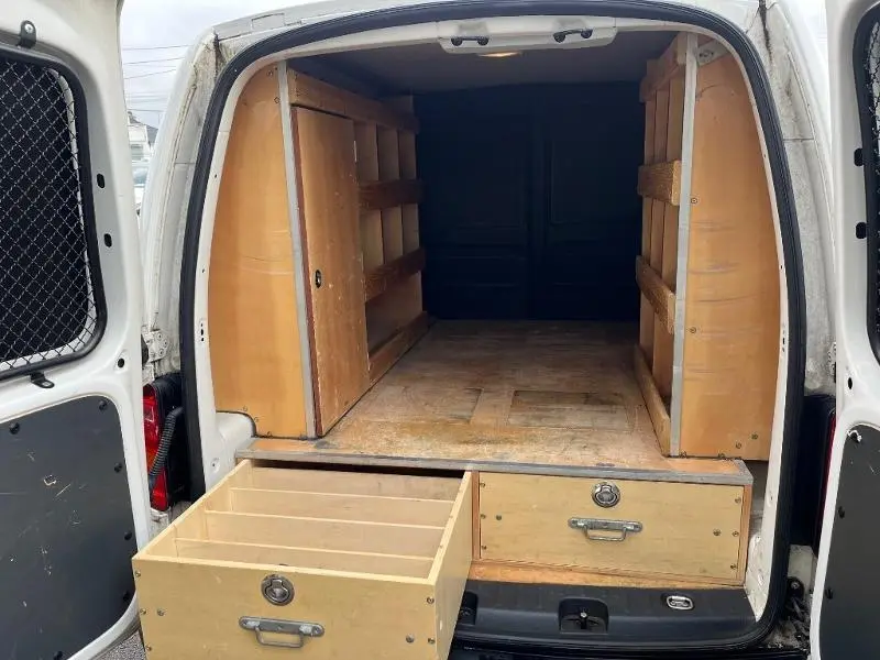 Vue arrière du Volkswagen Caddy Van blanc Candy 2016 avec portes ouvertes et aménagements bois dans l’espace de chargement.