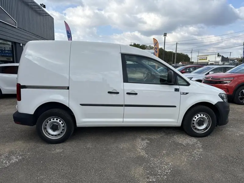 Profil droit d'un Volkswagen Caddy Van blanc Candy 2016 avec porte latérale coulissante et jantes acier 15 pouces.