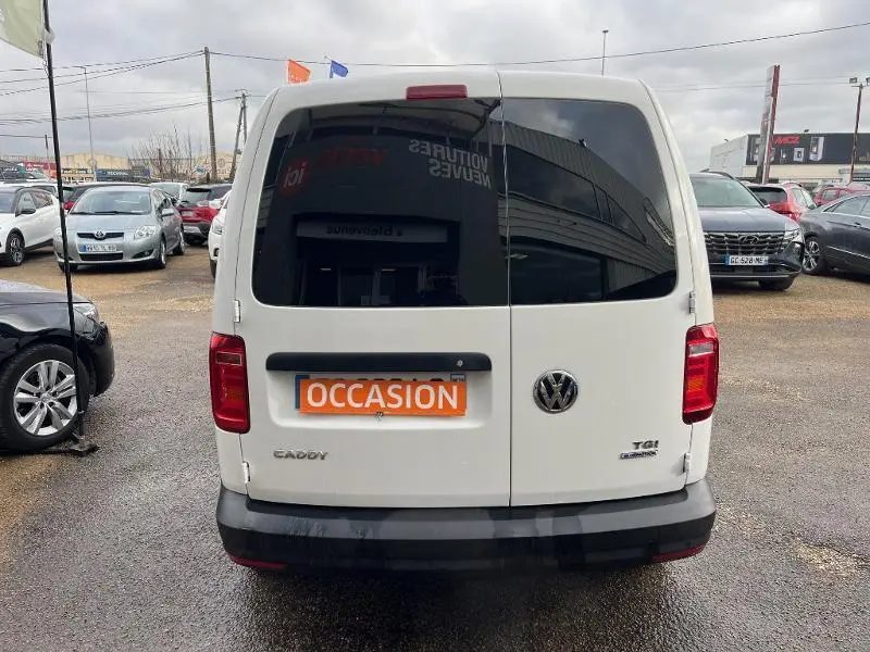 Vue arrière d'un Volkswagen Caddy Van blanc Candy avec portes battantes et logo VW visible, en concession.