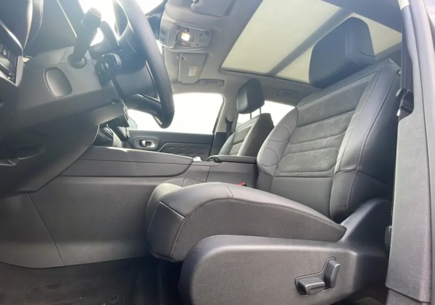 Intérieur du Citroën C5 Aircross Hybrid 2025 vu côté conducteur, sièges cuir noir et toit panoramique.