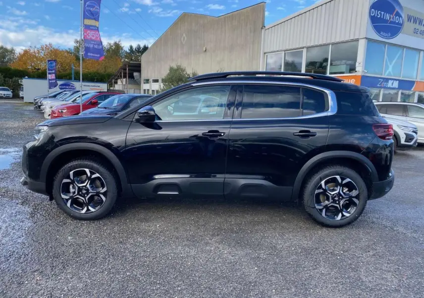 Profil côté gauche du Citroën C5 Aircross noir Perla avec jantes alliage 18'' bi-ton et barres de toit visibles.