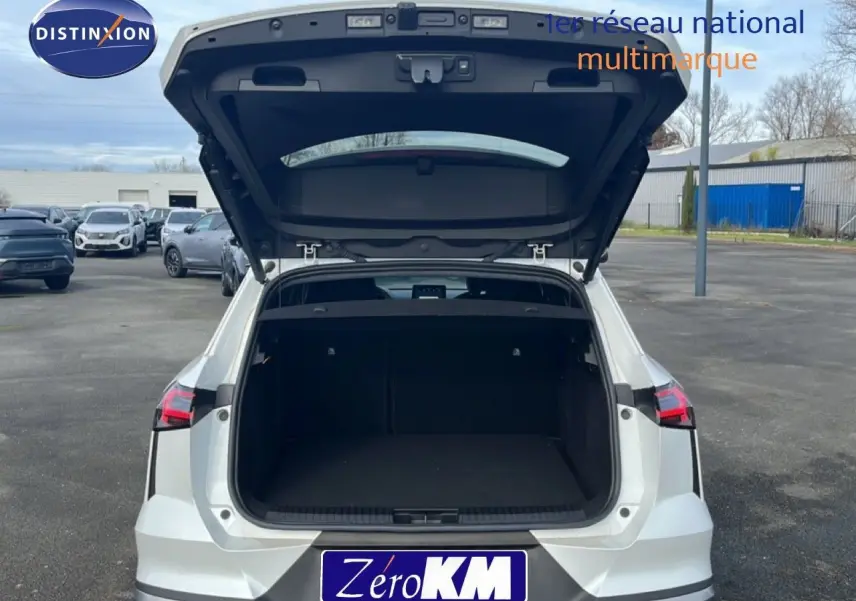 Vue arrière d’un Renault Symbioz blanc nacré métal 2025 avec coffre ouvert montrant un grand espace de chargement vide.