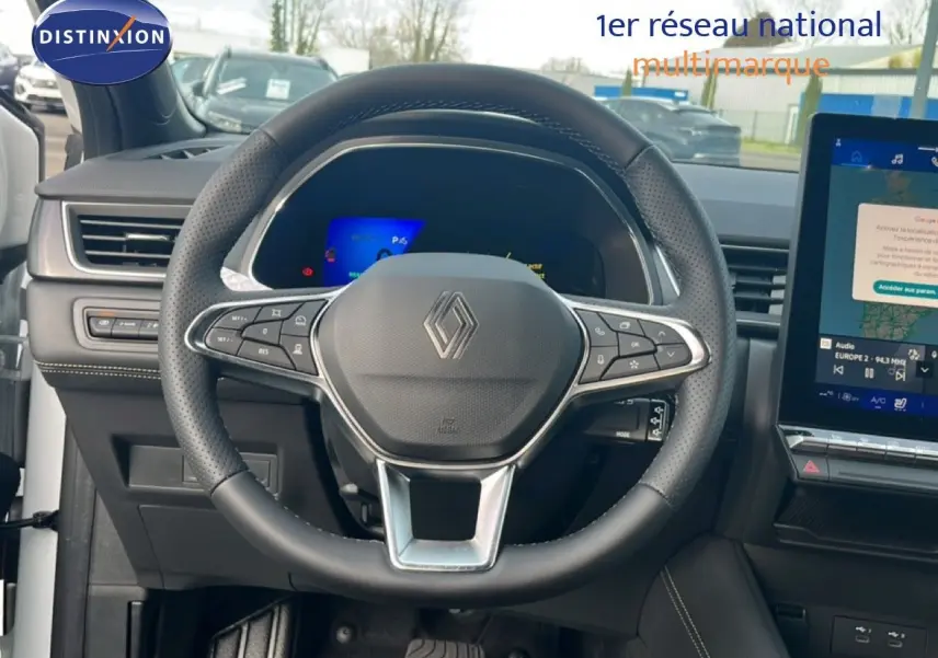 Vue intérieure centrée sur le volant en cuir noir et le tableau de bord numérique de la Renault Symbioz blanche nacrée 2025.
