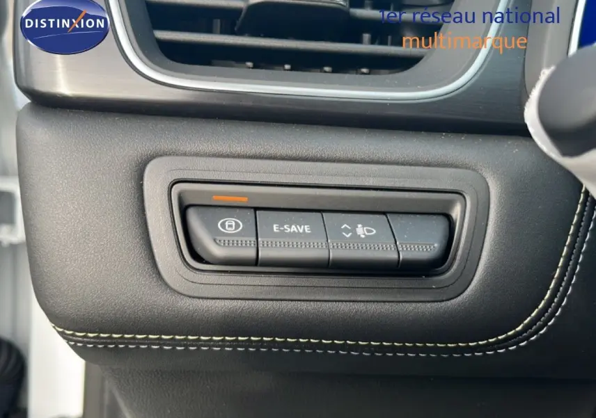 Gros plan sur les commandes de tableau de bord noir avec surpiqûres blanches dans la Renault Symbioz blanche nacrée.