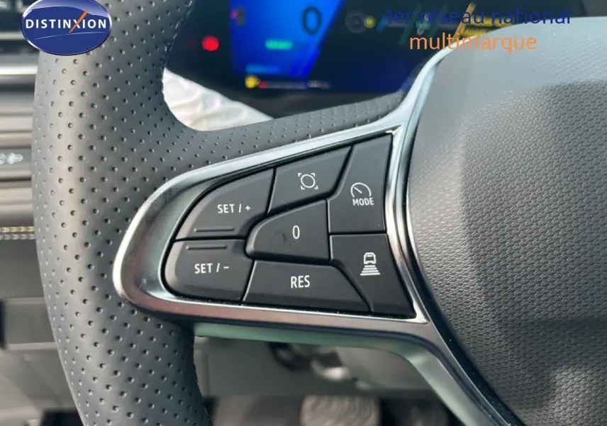 Gros plan sur les commandes de régulateur de vitesse au volant perforé d’une Renault Symbioz blanc nacré, intérieur moderne.