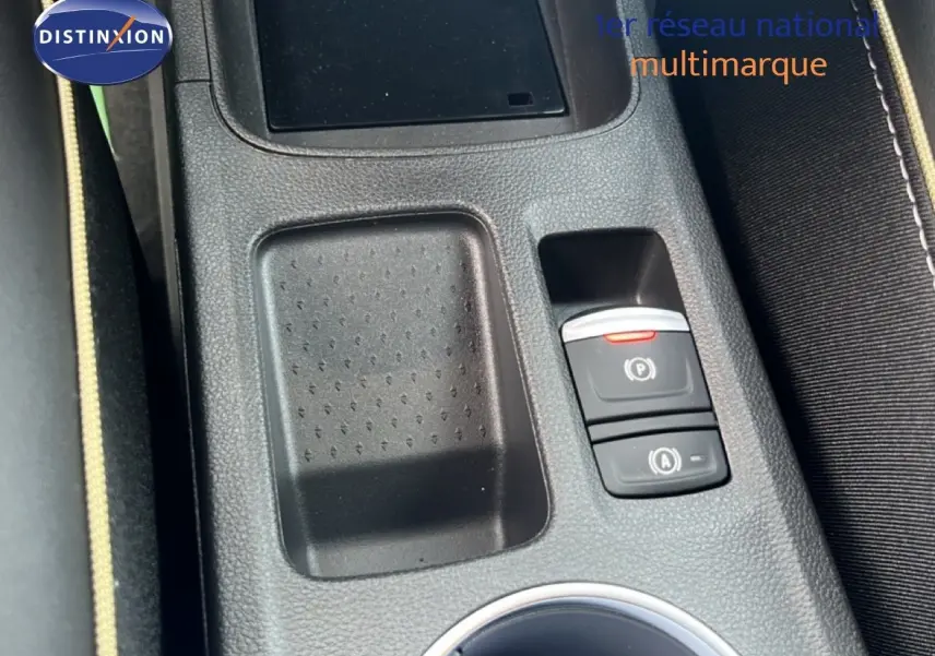 Gros plan sur la console centrale noire avec commandes de frein à main électrique et rangement du Renault Symbioz blanc nacré.