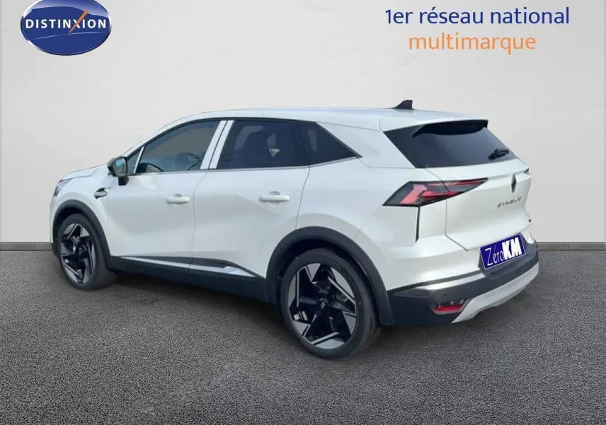 Renault Symbioz blanc nacré métal en vue 3/4 arrière droit, avec jantes noires et feux arrière LED distinctifs.
