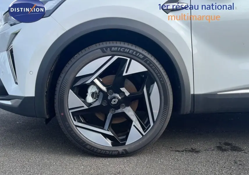 Gros plan sur la roue avant gauche du Renault Symbioz blanc nacré, mettant en valeur la jante noire et argentée au design moderne.